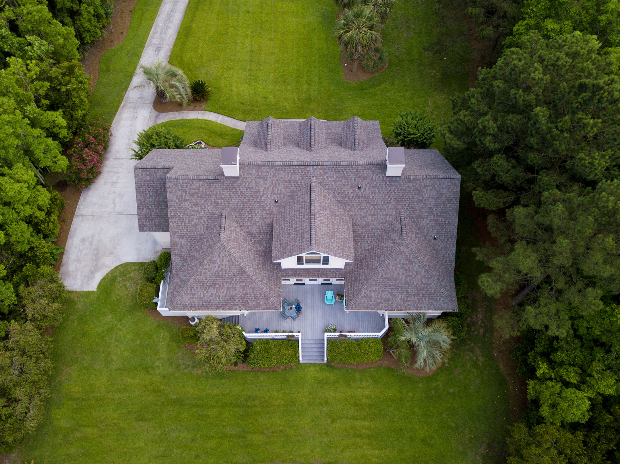 Aerial view of large home with new roof on beautiful property.